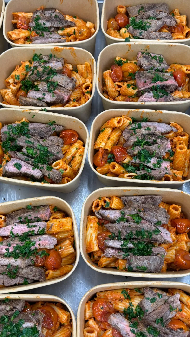 Rows of steak and rigatoni trays ready to be sealed